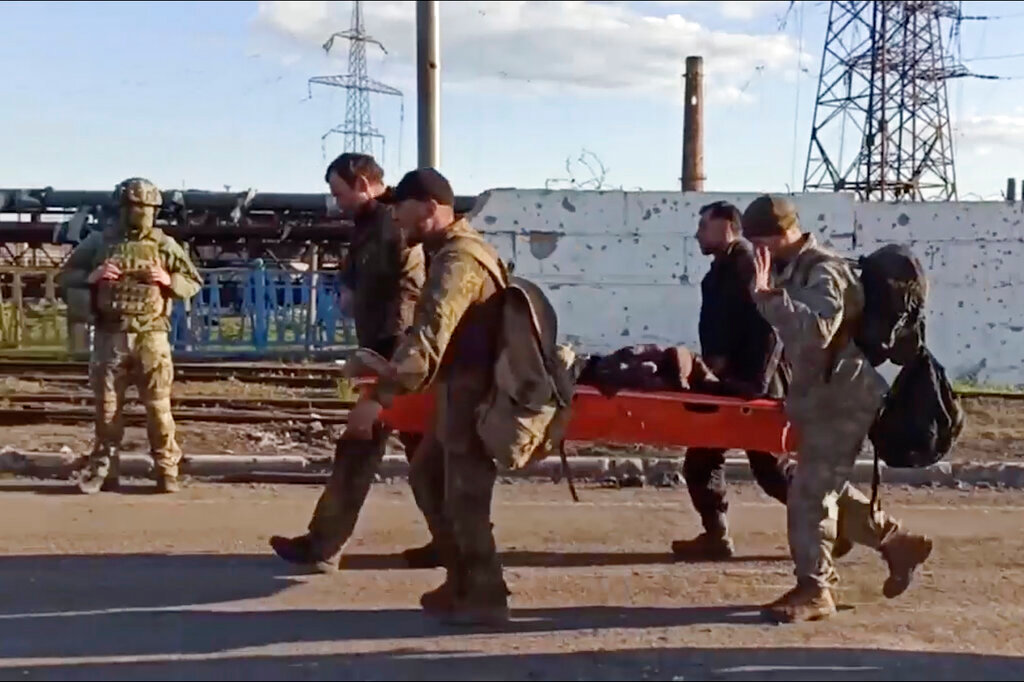 Ukrainian servicemen carry a wounded comrade as they are evacuated from the besieged Azovstal steel plant in Mariupol, Ukraine, Tuesday, May 17, 2022. More than 260 fighters, some severely wounded, were pulled from a steel plant on Monday that is the last redoubt of Ukrainian fighters in the city and transported to two towns controlled by separatists, officials on both sides said. (Russian Defense Ministry Press Service via AP)