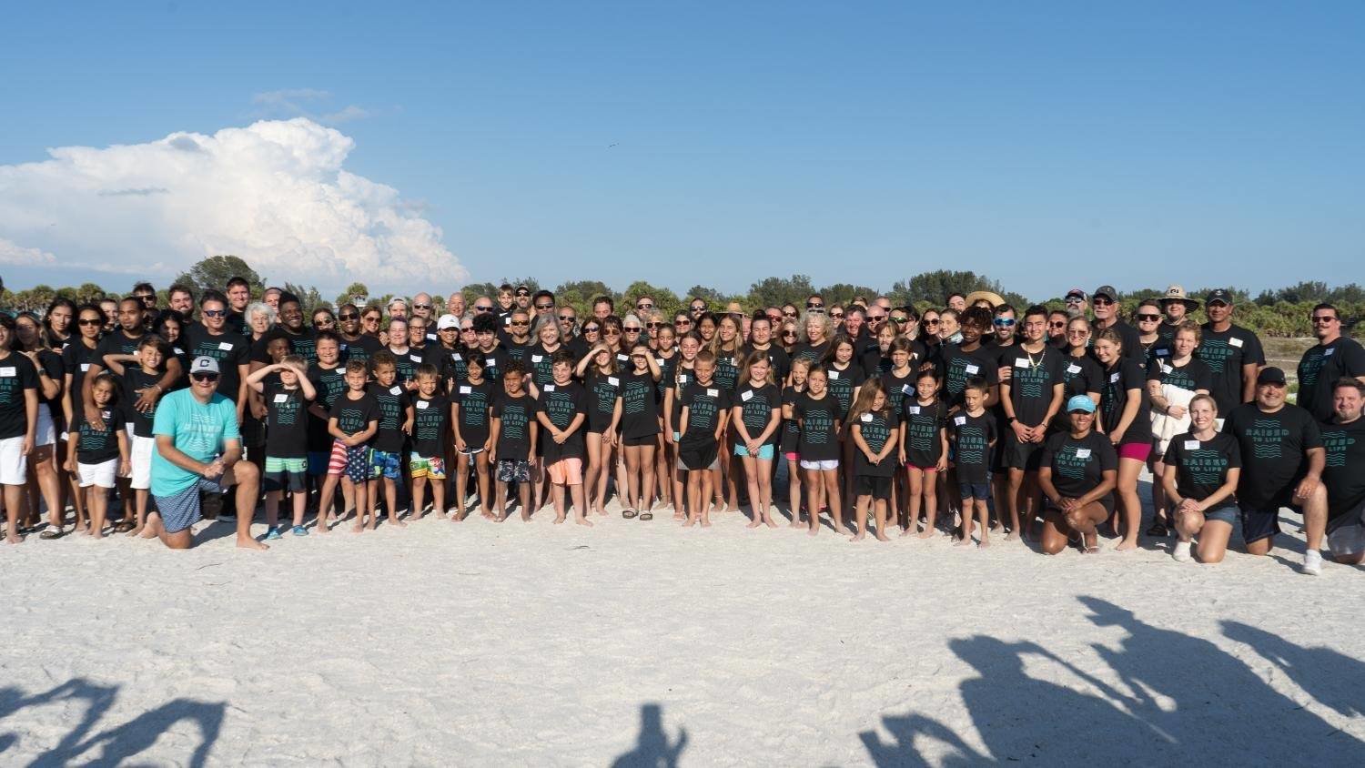 Calvary Church Pastor Willy Rice, kneeling in blue shirt, gathers with more than 130 new believers who took part in the church's beach baptism service May 15. (Photo from Willy Rice/Twitter)