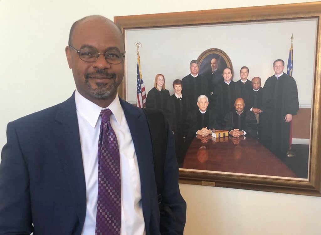 Former Georgia Supreme Court Chief Justice Harold Melton stands in front of a portrait of the Georgia Supreme Court that includes himself. (Capitol Beat Photo)