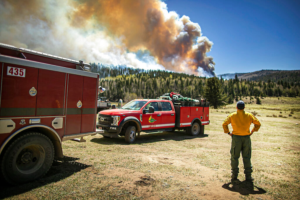Firefighter Ryan Le Baron with the Elk Creek fire department out of Colorado watches the fire blaze across a ridgeline near the Taos County line as firefighters from all over the country converge on Northern New Mexico to battle the Hermit's Peak and Calf Canyon fire on May 13, 2022. (Jim Weber/Santa Fe New Mexican via AP)
