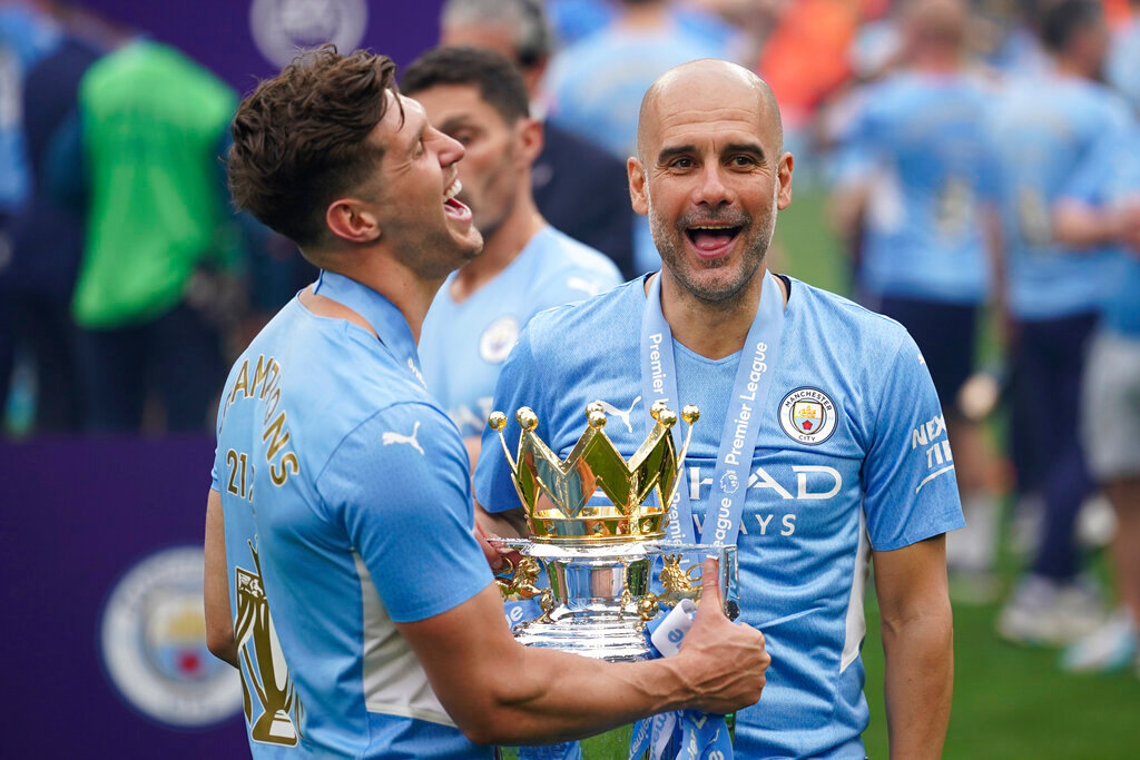 Manchester City's head coach Pep Guardiola, right, smiles with the trophy after winning the 2022 English Premier League title in Manchester, England, Sunday, May 22, 2022. (AP Photo/Dave Thompson)