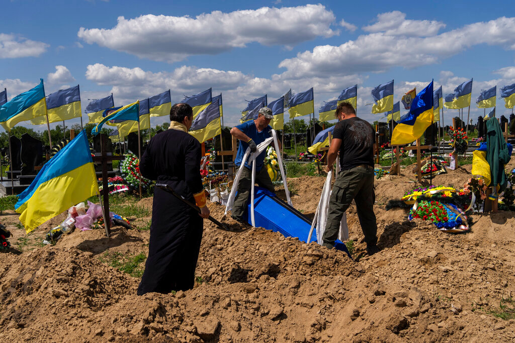Undertakers lower the coffin of Ukrainian serviceman Oleksander Matyukhin, 32, in Kharkiv, eastern Ukraine, Monday, May 23, 2022. (AP Photo/Bernat Armangue)