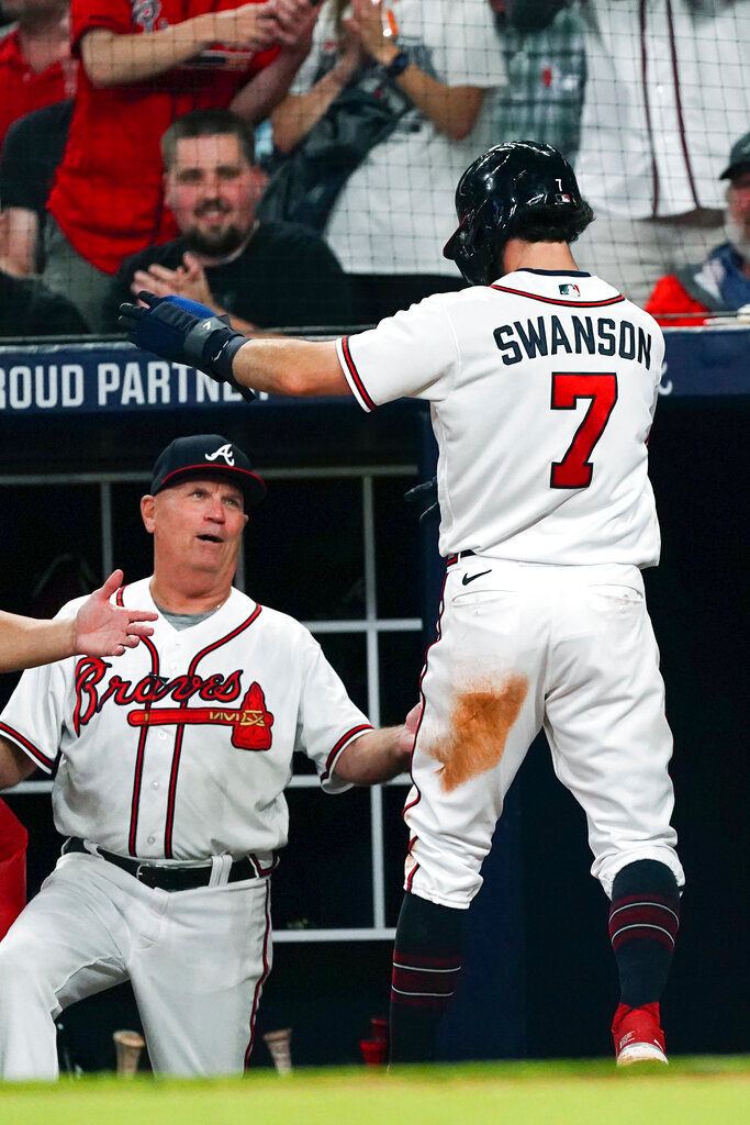 Atlanta Braves’ Dansby Swanson (7) is greeted by manager Brian Snitker after scoring on a wild pitch and a fielding error in the fifth inning against the Philadelphia Phillies  Wednesday, May 25, 2022, in Atlanta. (AP Photo/John Bazemore)
