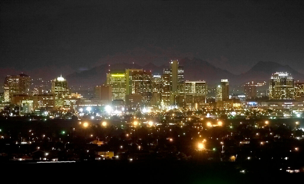 The Squaw Peak Mountains are seen behind the illuminated Phoenix skyline on February 28, 2002, from South Mountain in Phoenix. (AP Photo/Mel Evans, File)