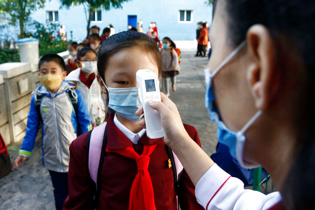 A teacher takes the temperature of a schoolgirl to help curb the spread of the coronavirus before entering Kim Song Ju Primary School in Central District in Pyongyang, North Korea, Oct. 13, 2021. (AP Photo/Cha Song Ho, File)
