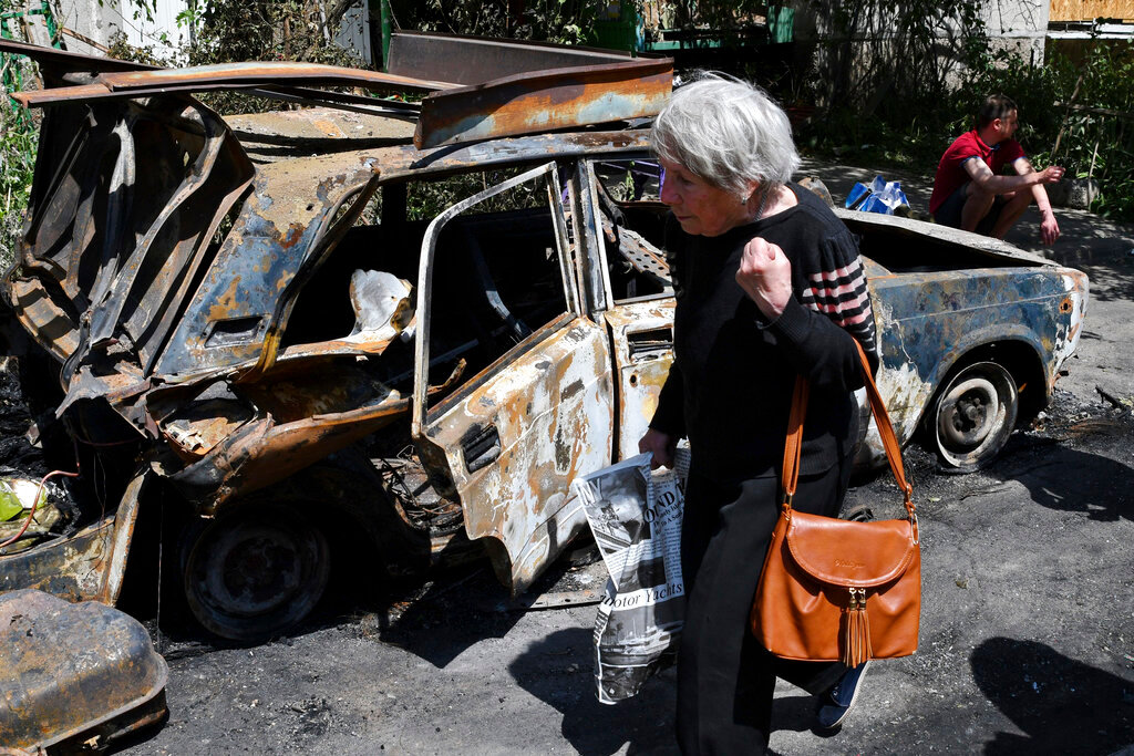 An elderly woman walks past a car damaged by an overnight missile strike in Sloviansk, Ukraine, Tuesday, May 31, 2022. (AP Photo/Andriy Andriyenko)