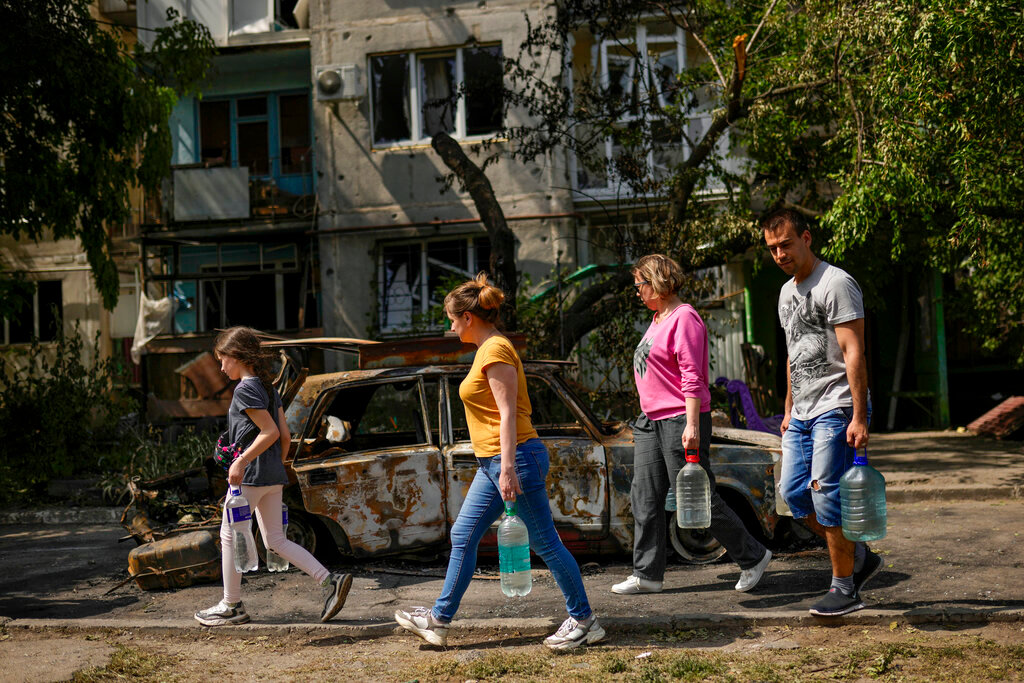 Residents carry water in front of an apartment building damaged in an overnight missile strike, in Sloviansk, Ukraine, Tuesday, May 31, 2022. (AP Photo/Francisco Seco)