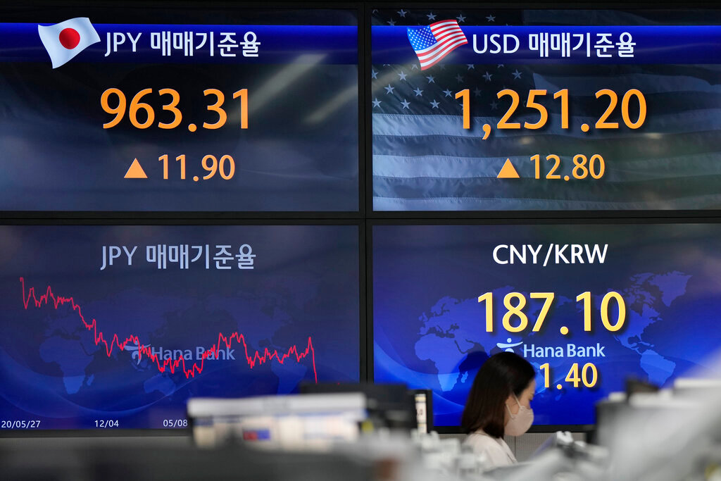 A currency trader walks by the screens showing the foreign exchange rates at a foreign exchange dealing room in Seoul, South Korea, Friday, June 3, 2022. (AP Photo/Lee Jin-man)
