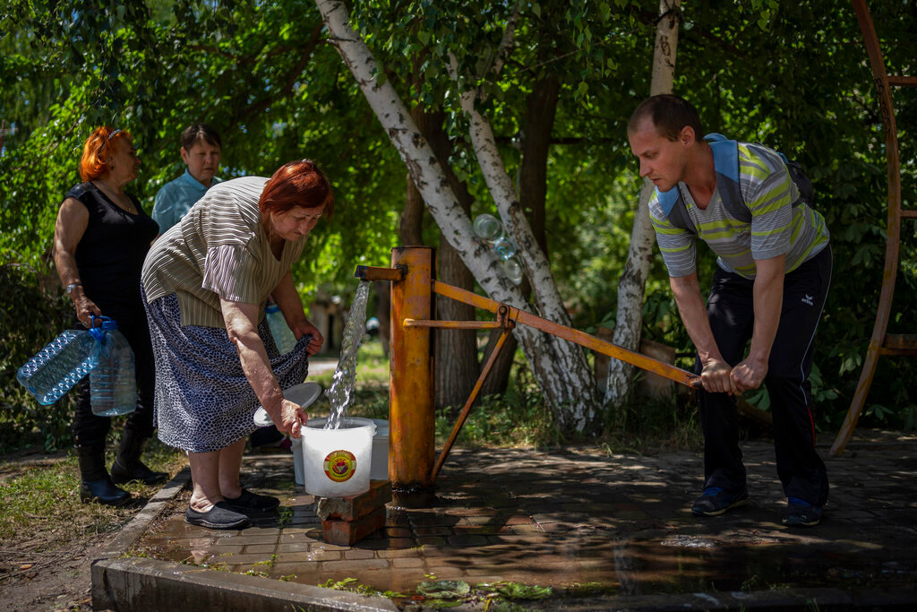 Residents gather to collect water from a pump in the street in Sloviansk, Ukraine, on Thursday, June 2, 2022. (AP Photo/Elena Becatoros)