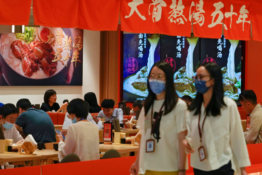 Women wearing face masks walk past a reopened restaurant in a shopping mall in Beijing Monday, June 6, 2022. (AP Photo/Andy Wong)