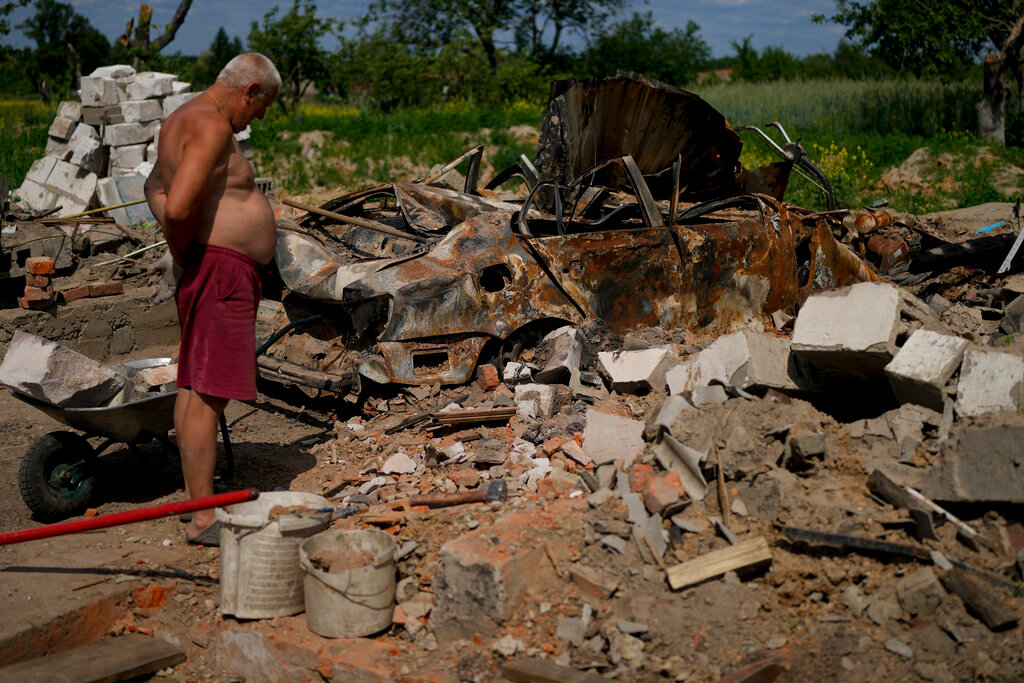 A man looks at what is left of his home and car after attacks in Yasnohorodka, on the outskirts of Kyiv, Ukraine, Wednesday, June 8, 2022. (AP Photo/Natacha Pisarenko)