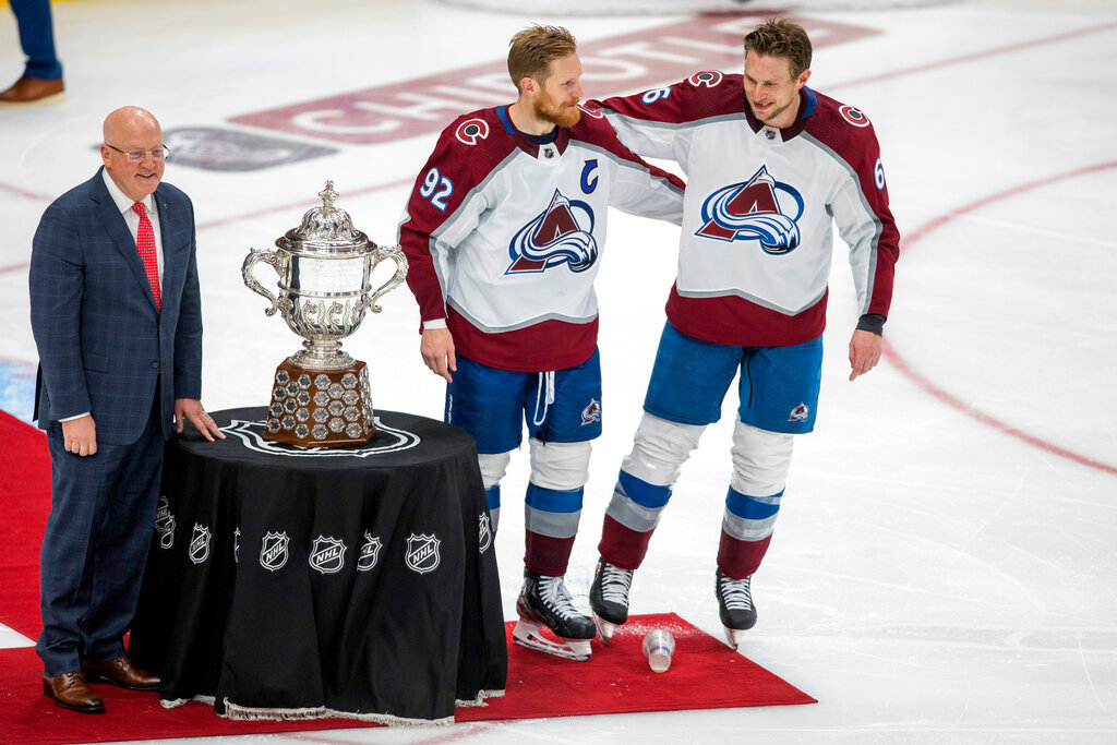 Colorado Avalanche's Gabriel Landeskog (92) and Erik Johnsonstand with the Campbell Conference Bowl as Deputy Commissioner Bill Daley looks on after the Avalanche won the NHL conference finals in Edmonton, Alberta, Monday, June 6, 2022. (Amber Bracken/The Canadian Press via AP)