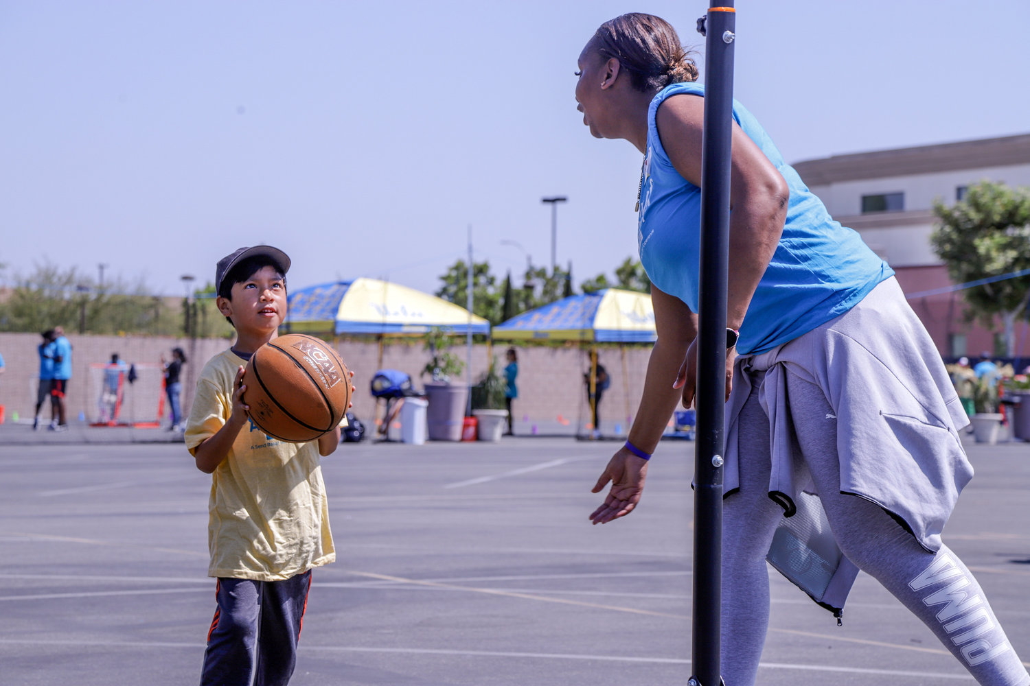 Cynthia Baker, a member of First Southern Baptist Church of Anaheim, Calif., encourages a child to shoot a basket during a sports camp at the church June 11, 2022, as part of Crossover Anaheim. The event was one of several evangelistic events held across the greater Los Angeles area prior to the 2022 SBC Annual Meeting. (NAMB/Luc Stringer)