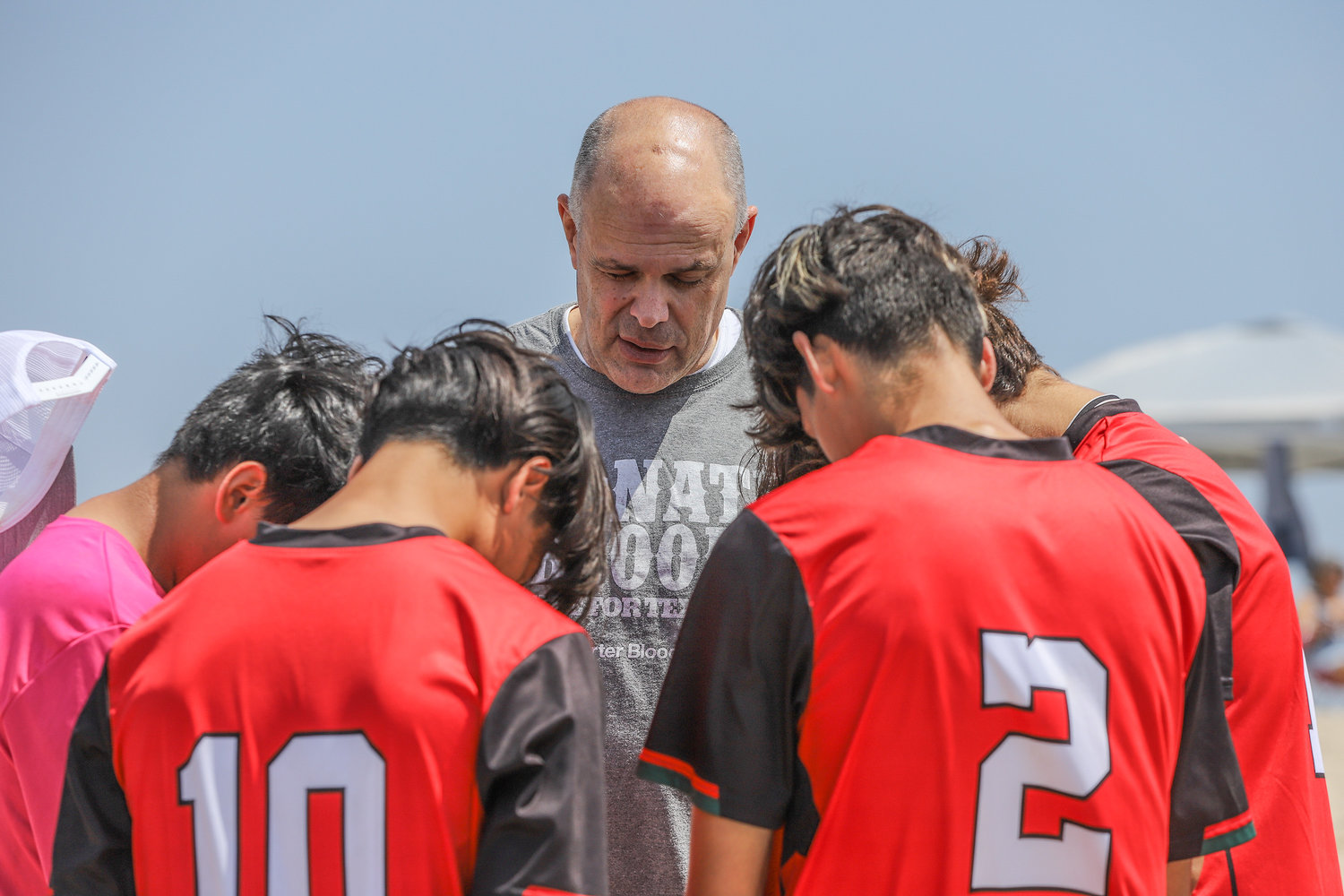 Pastor David Rose, center, of First Baptist Church of Winnsboro, Texas, prays with members of the Desert United Soccer Club at Huntington State Beach Park in Huntington Beach, Calif., June 11, 2022. The Garage Church in Huntington Beach sponsored a surf camp as part of Crossover Anaheim – an evangelistic outreach across the greater Los Angeles area prior to the Southern Baptist Convention annual meeting. (NAMB/Sonya Singh)