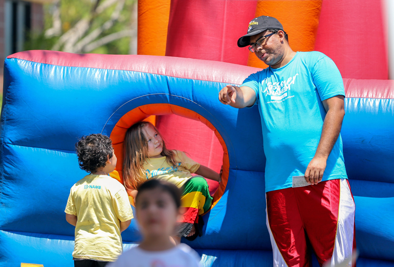 Prashant Joseph, a member of First Southern Baptist Church of Anaheim, Calif., assists kids on a bounce house at a block party at Friends Baptist Church in Yorba Linda, Calif., June 11, 2022. The evangelistic event, part of Crossover Anaheim, included free food, a fitness boot camp, prizes and games. (NAMB/Sonya Singh)