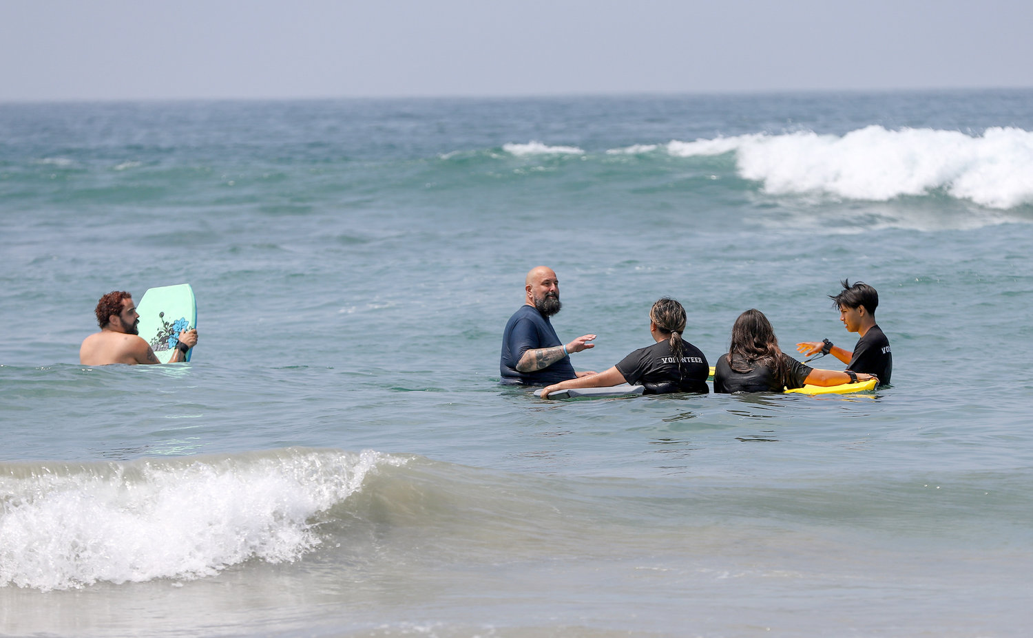 Curtis Lohman, center, pastor of The Garage Church at Huntington Beach, Calif., teaches body boarding to participants of Project Support Anaheim’s Youth, a local youth development program, at Huntington State Beach Park on June 11 as part of Crossover Anaheim. (NAMB/Sonya Singh)