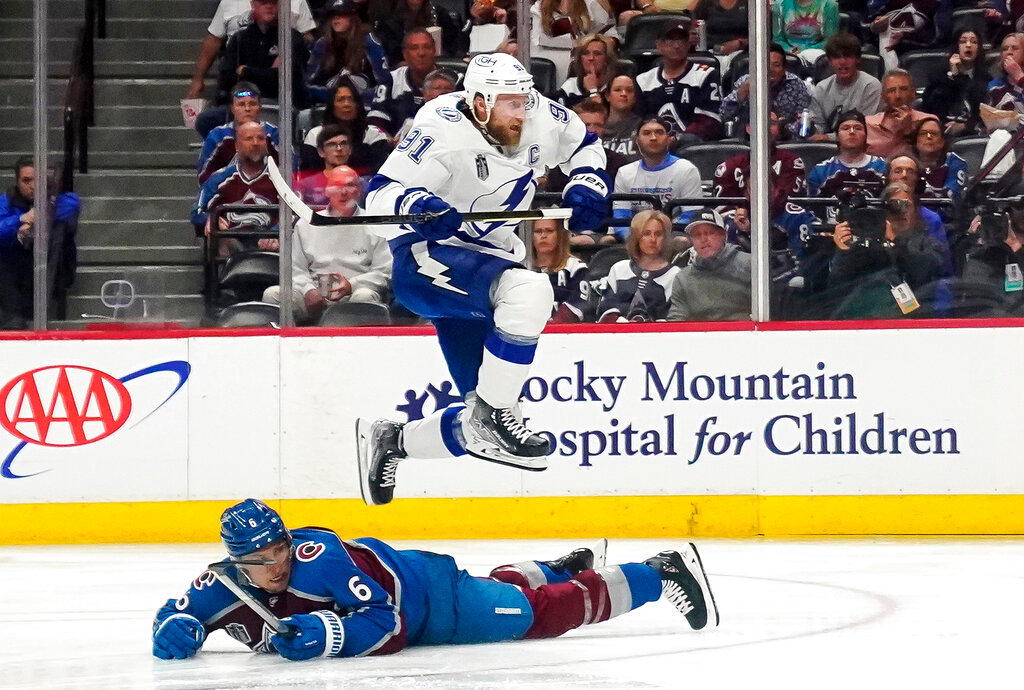 Tampa Bay Lightning center Steven Stamkos (91) jumps over Colorado Avalanche defenseman Erik Johnson (6) during the second period of Game 1 of the NHL Stanley Cup Final on Wednesday, June 15, 2022, in Denver. (AP Photo/John Locher)