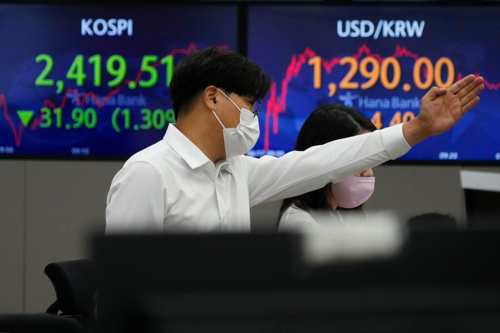 A currency trader gestures in front of the screens showing the Korea Composite Stock Price Index), left, and the exchange rate of South Korean won against the U.S. dollar at the foreign exchange dealing room of the KEB Hana Bank headquarters in Seoul, South Korea, Friday, June 17, 2022. (AP Photo/Ahn Young-joon)