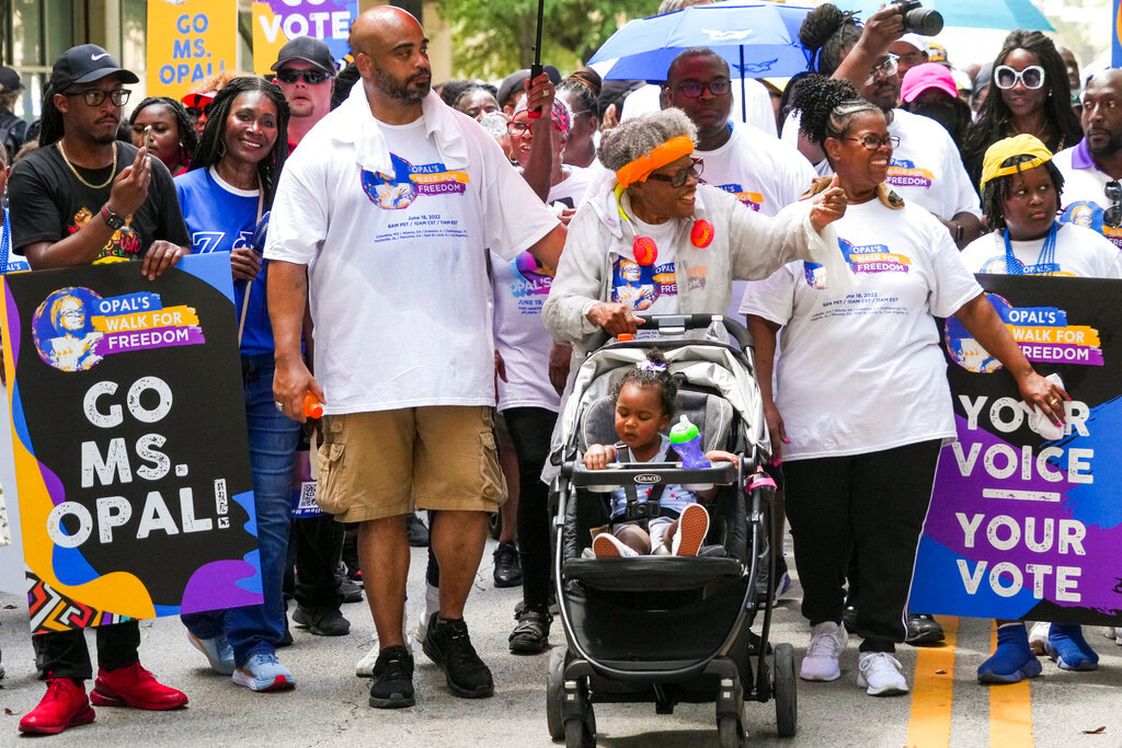 Opal Lee pushes one of her great granddaughters in a stroller as she waves to musicians playing along the route during the 2022 Opal's Walk for Freedom on Saturday, June 18, 2022, in Fort Worth. Lee, often referred to as the "Grandmother of Juneteenth" led her annual two-and-a-half-mile walk, representing the number of years after the Emancipation Proclamation before enslaved people in Texas learned they were free. (Smiley N. Pool/The Dallas Morning News via AP)