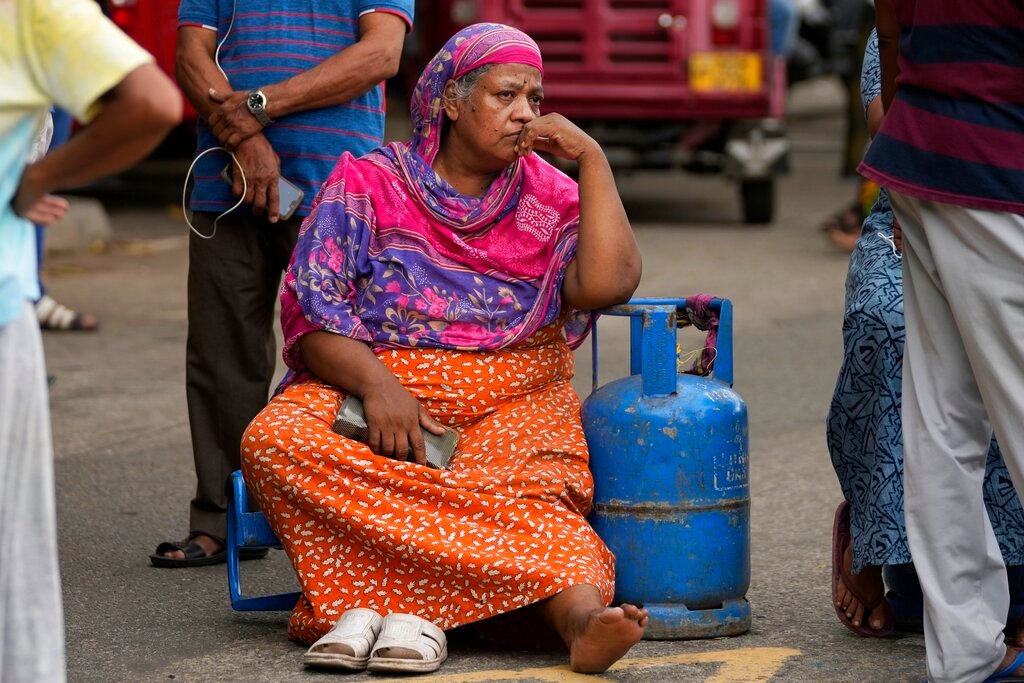 An elderly woman sits outside a police station in a protest demanding cooking gas in Colombo, Sri Lanka, Saturday, May 14, 2022. (AP Photo/Eranga Jayawardena, file)