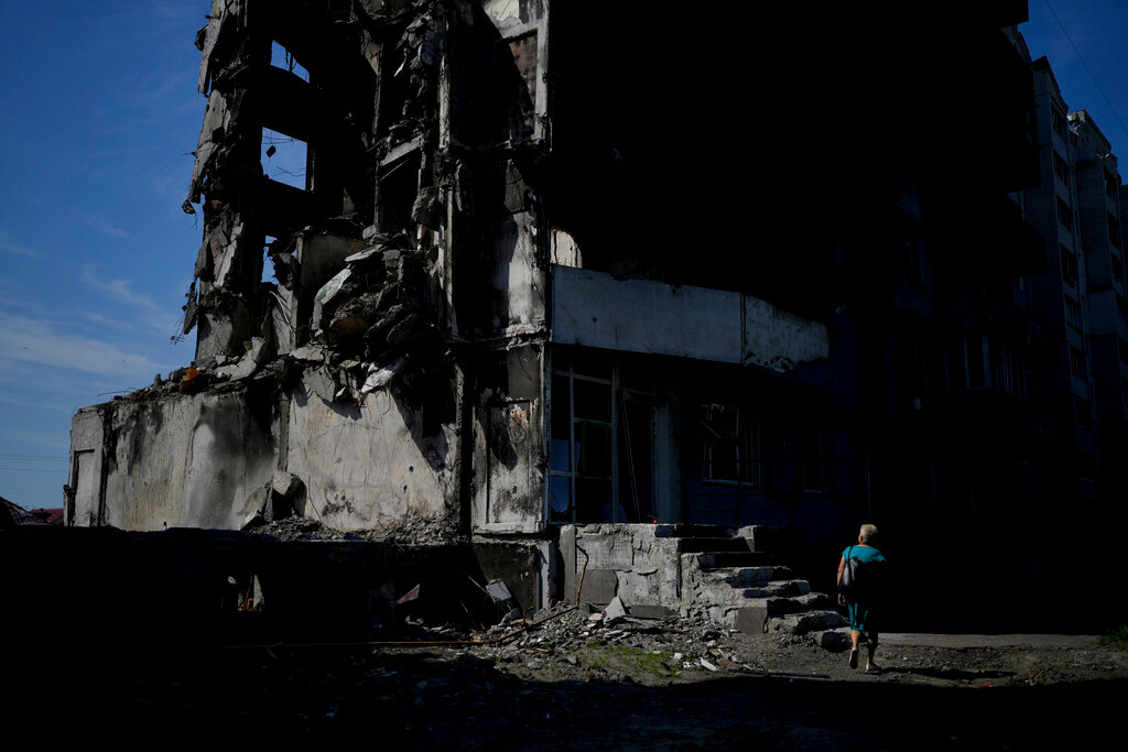 A woman walks past a building destroyed in Russian shelling in Borodyanka, on the outskirts of Kyiv, Ukraine, Tuesday, June 21, 2022. (AP Photo/Natacha Pisarenko)