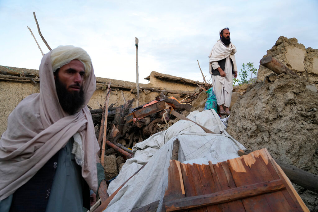 Afghans stand among destruction after an earthquake in Gayan village, in Paktika province, Afghanistan, Thursday, June 23, 2022. (AP Photo/Ebrahim Nooroozi)