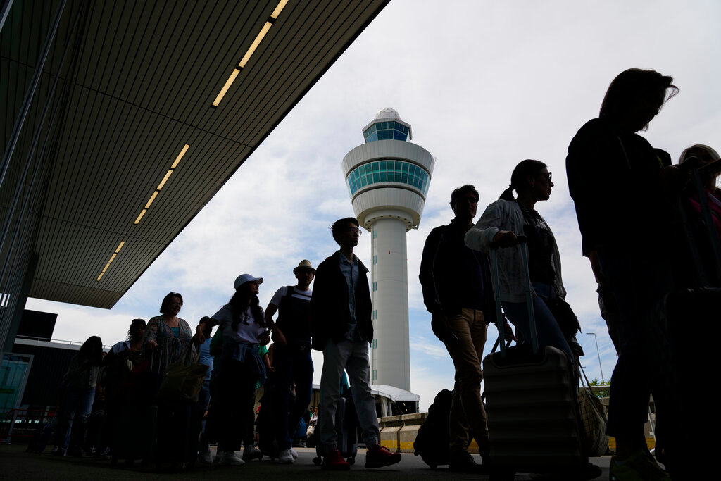 Travelers wait in long lines outside the terminal building to check in and board flights at Amsterdam's Schiphol Airport, Netherlands, Tuesday, June 21, 2022. (AP Photo/Peter Dejong)