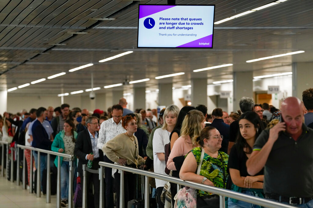 Travelers wait in long lines to check in and board flights at Amsterdam's Schiphol Airport, Netherlands, Tuesday, June 21, 2022. (AP Photo/Peter Dejong)