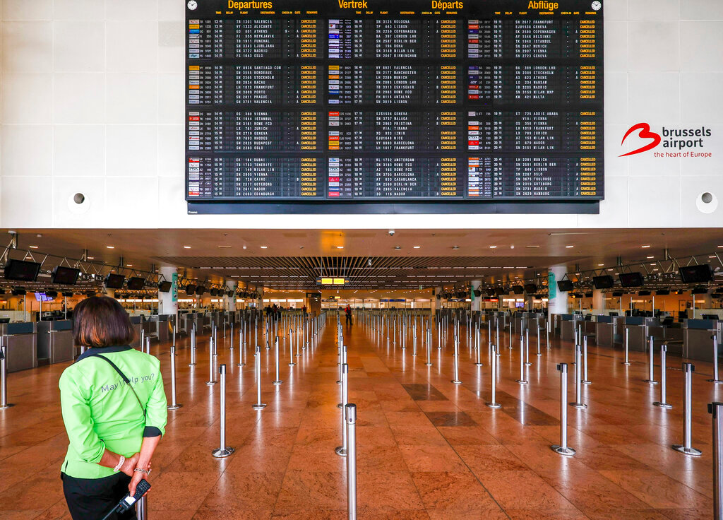 An employee stands under a departures board with cancelled flights in the departures hall at Brussels international airport during a general strike in Brussels, Monday, June 20, 2022. (AP Photo/Olivier Matthys)