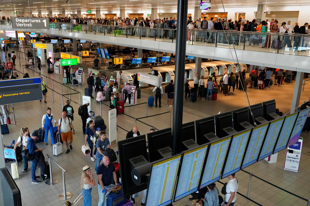 Travelers wait in long lines to check in and board flights at Amsterdam's Schiphol Airport, Netherlands, Tuesday, June 21, 2022. (AP Photo/Peter Dejong)