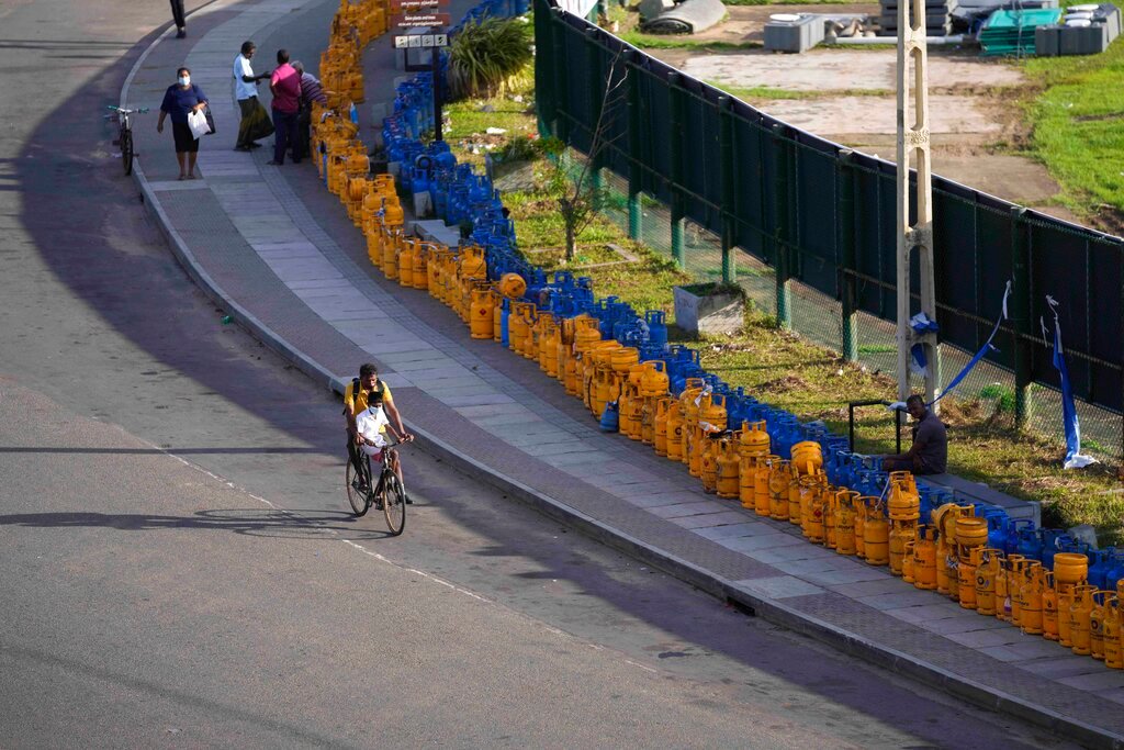 A man rides past empty gas canisters placed in line beside the Galle International Cricket Stadium in Galle, Sri Lanka, Tuesday, June 28, 2022. (AP Photo/Eranga Jayawardena)