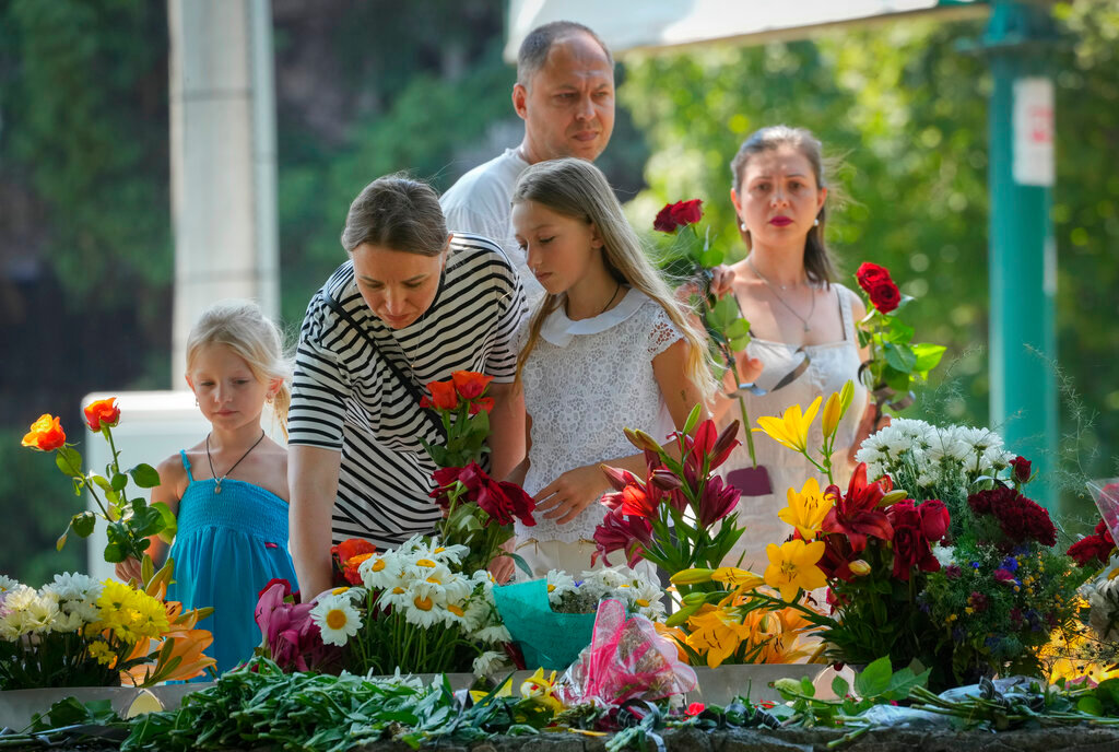People lay flowers in memory of victims of the Russian rocket attack on a shopping center in Kremenchuk, Ukraine, Wednesday, June 29, 2022. (AP Photo/Efrem Lukatsky)
