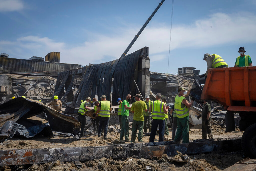 Workers clear debris at a shopping center that was destroyed in a Russian rocket attack in Kremenchuk, Ukraine, Wednesday, June 29, 2022. (AP Photo/Efrem Lukatsky)