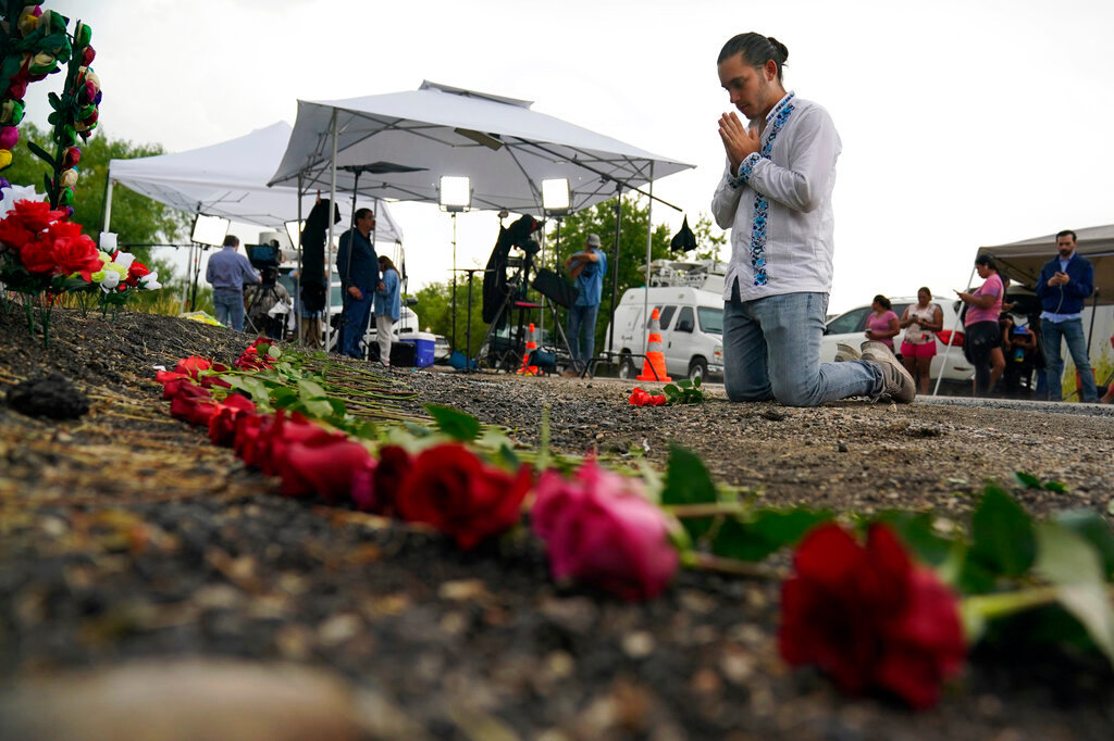 Carlow Eduardo Espina prays Tuesday, June 28, 2022, after placing roses on a make-shift memorial at the site where officials found dozens of people dead Monday in a semitrailer containing suspected migrants in San Antonio. (AP Photo/Eric Gay)