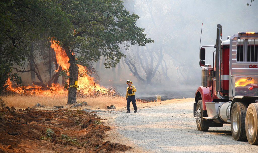 A firefighter assesses the approaching fire along Troost Trail in California's rural Nevada County, Tuesday, June 28, 2022. (Elias Funez/The Union via AP)
