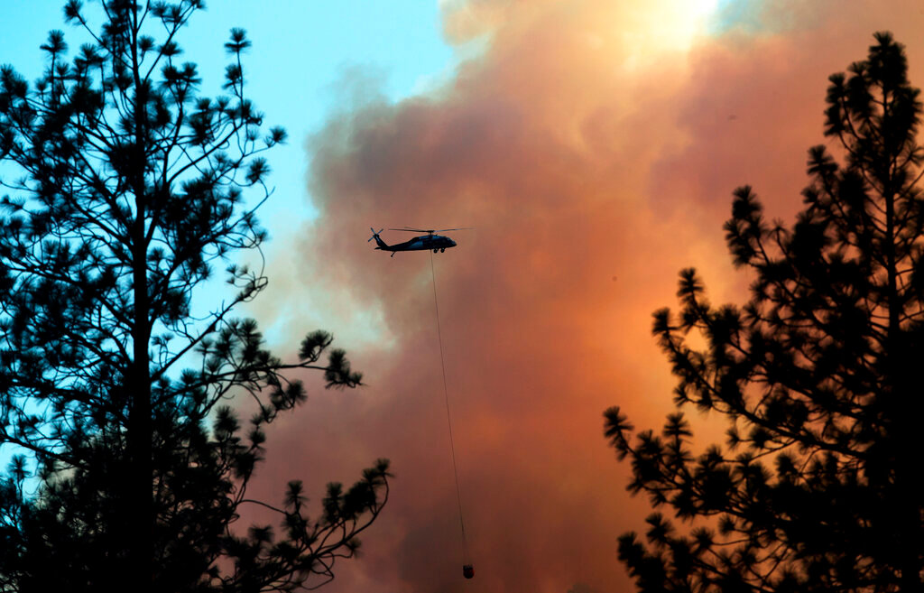 A helicopter drops water on the mountainside near French Corral, Calif., on Tuesday, June 28, 2022. (Carlos Avila Gonzalez/San Francisco Chronicle via AP)