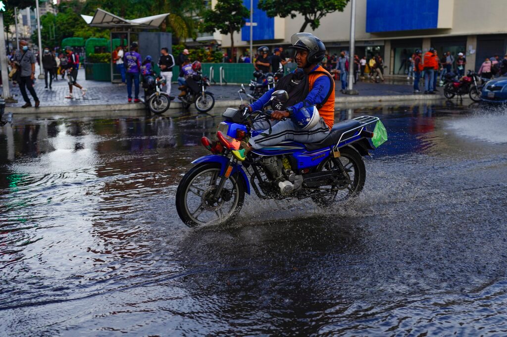 A man rides his motorcycle over a puddle in Caracas, Venezuela, Wednesday, June 29, 2022. (AP Photo/Ariana Cubillos)