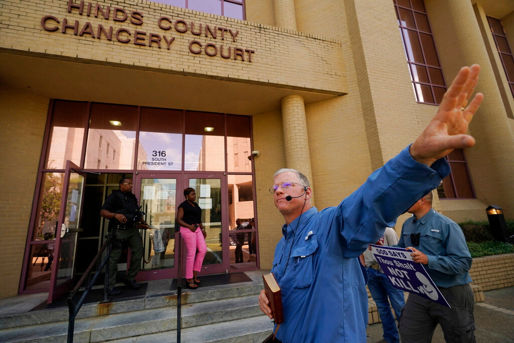 Pro-life activist Coleman Boyd, who is also a physician, holds his Bible and calls out at people entering and leaving the Hinds County Chancery Court, Tuesday, July 5, 2022, in Jackson, Miss. (AP Photo/Rogelio V. Solis)