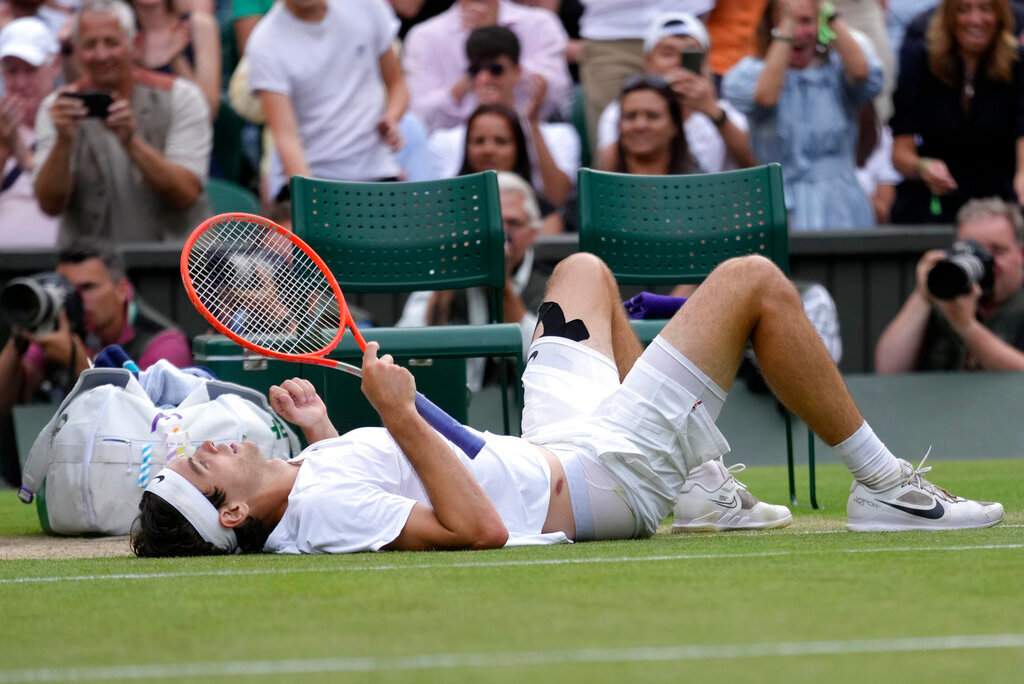 Taylor Fritz of the US lays on the court after falling trying to return to Spain's Rafael Nadal in a men's singles quarterfinal match at the Wimbledon tennis championships in London, Wednesday, July 6, 2022. (AP Photo/Kirsty Wigglesworth)