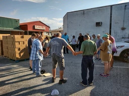 Volunteers pray to bless the food before distributing meals to children. (Photo/Emanuel Baptist Association)
