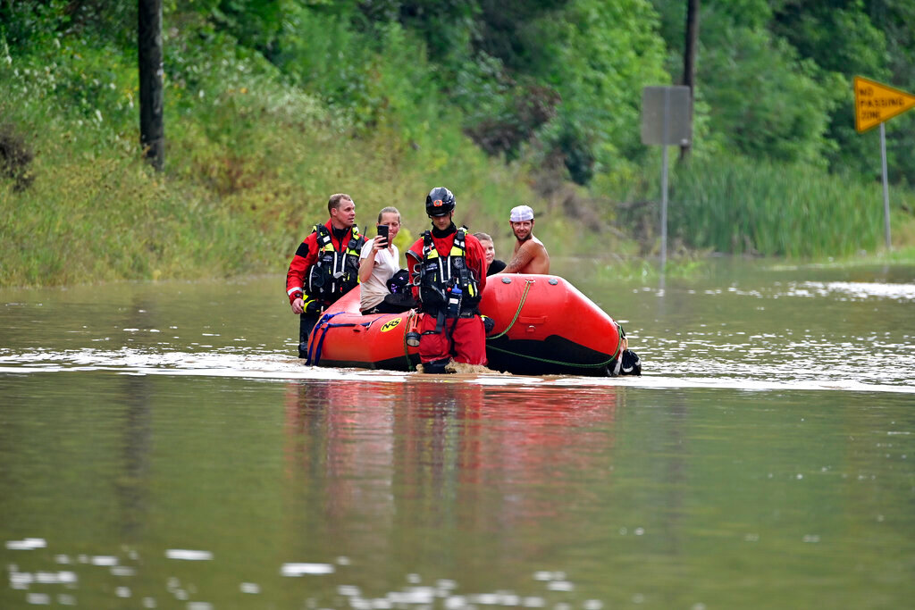 Members of the Winchester, Ky., Fire Department walk inflatable boats across flood waters over Ky. State Road 15 in Jackson, Ky., to pick up people stranded by the floodwaters Thursday, July 28, 2022. (AP Photo/Timothy D. Easley)