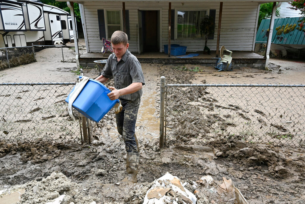 A boy removes mud filled debris from homes following flooding  in Hindman, Ky., Saturday, July 30, 2022. (AP Photo/Timothy D. Easley)