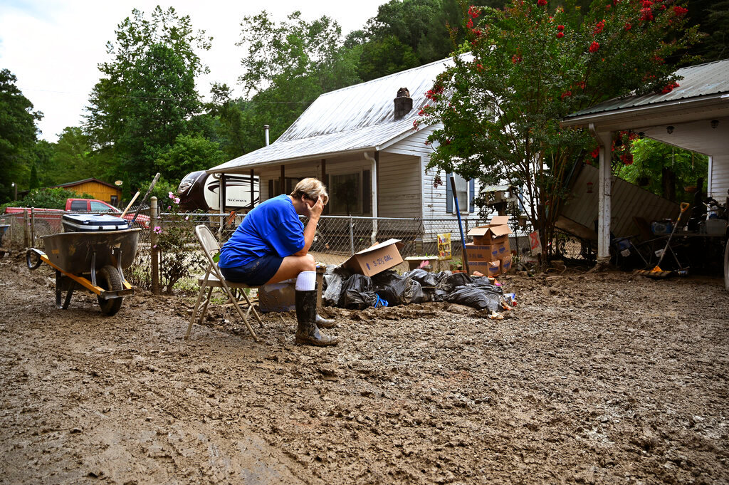 Teresa Reynolds sits exhausted as members of her community clean the debris from their flood ravaged homes at Ogden Hollar in Hindman, Ky., Saturday, July 30, 2022. (AP Photo/Timothy D. Easley)