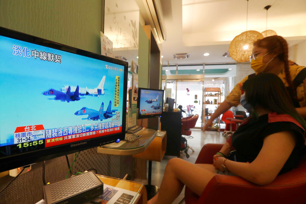 A customer and a staff member watch a news report on the recent tensions between China and Taiwan, at a beauty salon in Taipei, Taiwan, Thursday, Aug. 4, 2022. (AP Photo/Chiang Ying-ying)