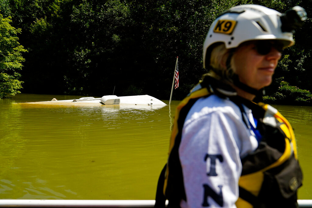 A submerged camper with an American flag attached is seen as Jackie Johnson rides by in a boat in Carr Creek Lake on Wednesday, Aug. 3, 2022, near Hazard, Ky. (AP Photo/Brynn Anderson)