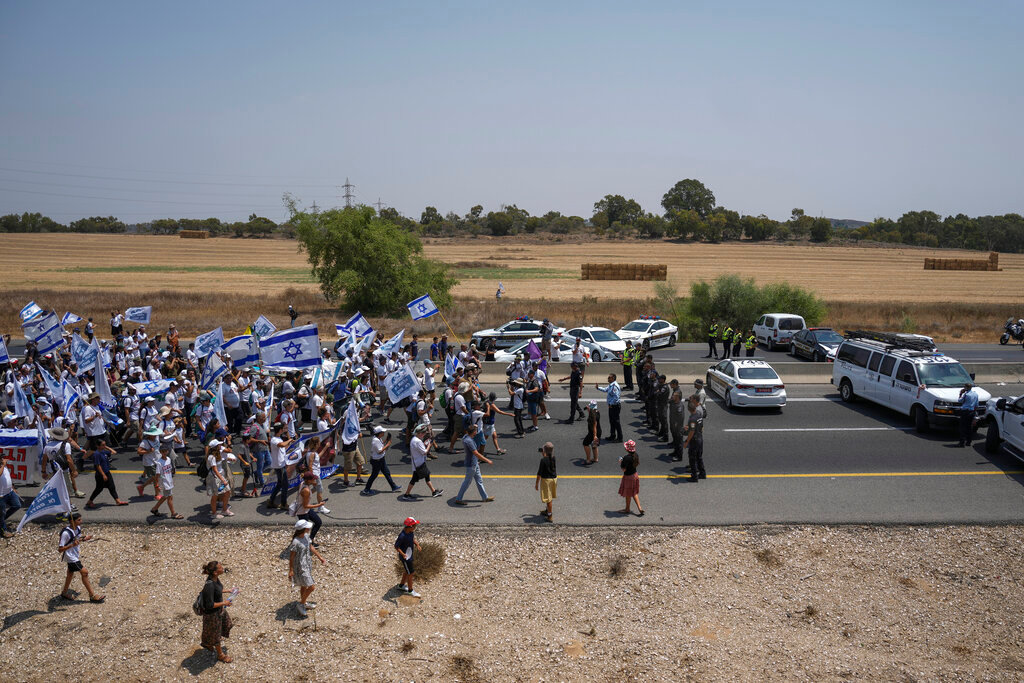 Israeli police officers try to block supporters and family members of Israeli soldier Hadar Goldin, killed during the 2014 conflict in the Gaza Strip, from marching towards the Gaza border near Kibbutz Yad Mordechai, southern Israel Friday, Aug. 5, 2022. (AP Photo/Ariel Schalit)