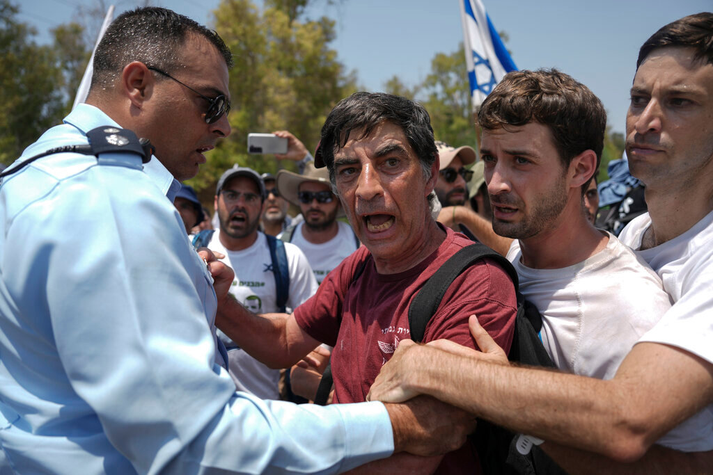 An Israeli police officer tries to block Simha Goldin, center, father of Israeli soldier Hadar Goldin, killed during the 2014 conflict in the Gaza Strip, from marching towards the Gaza border near Kibbutz Yad Mordechai, southern Israel Friday, Aug. 5, 2022. (AP Photo/Ariel Schalit)