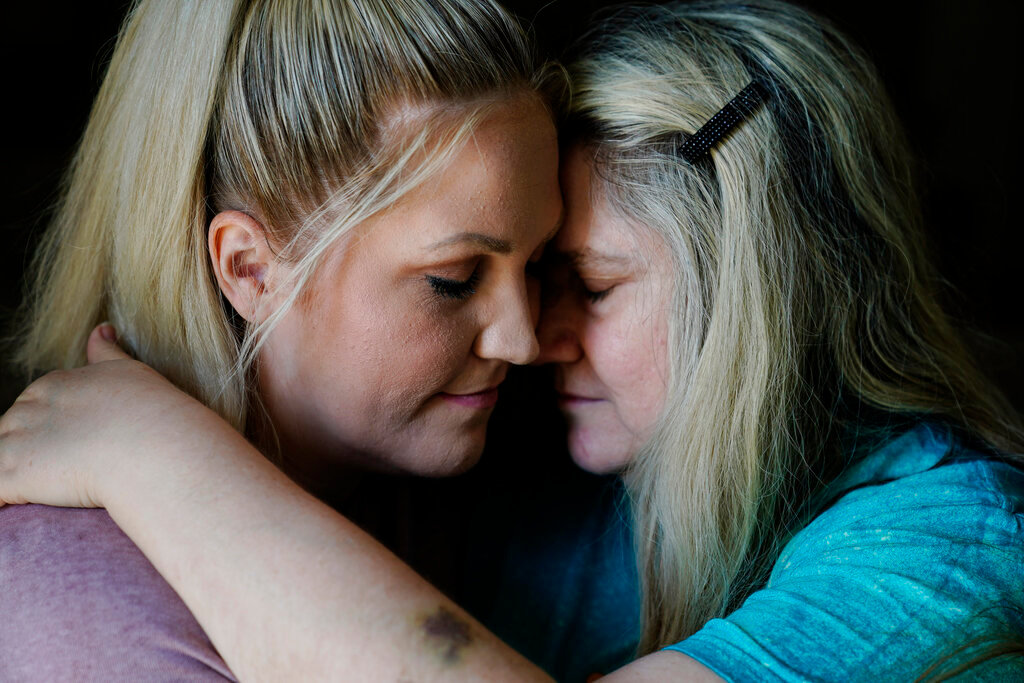 Angel Campbell, left, embraces her mother Patricia Collins, right, on Thursday, Aug. 4, 2022, in Chavies, Ky. Collins was badly injured in massive flooding. (AP Photo/Brynn Anderson)