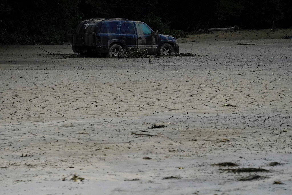 A vehicle is abandoned and surrounded by mud caused by last week's massive flooding near Haddix, Ky., Friday, Aug. 5, 2022. (AP Photo/Brynn Anderson)