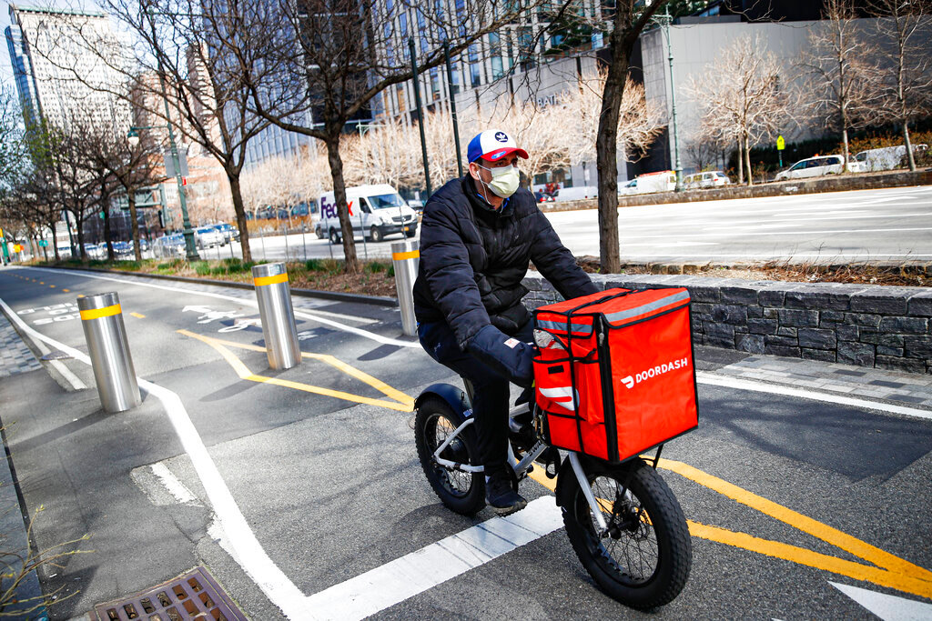 A delivery worker rides his bicycle along a path on the West Side Highway in New York, March 16, 2020. (AP Photo/John Minchillo, File)